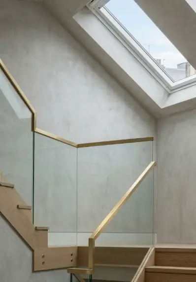 Loft staircase with oak treads and a brass-framed glass balustrade beneath a skylight